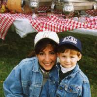 An alum smiles for a photo with a young child